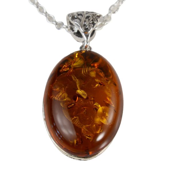 Lois oval Baltic honey amber pendant in 925 sterling silver with floral filigree bail, genuine natural amber cabochon necklace showing organic inclusions on white background