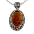 Side view of Lois oval Baltic honey amber pendant in 925 sterling silver showing floral filigree openwork setting and genuine amber cabochon with natural inclusions on white background