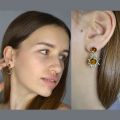 Model wearing genuine Baltic honey amber “Sun” earrings in 925 sterling silver—two-tone amber stud with dangling sunburst charm, shown in face view and close-up on ear.