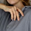Woman wearing a sterling silver ring with oval Baltic amber stone on her hand, shown in a lifestyle close-up.