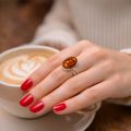 Woman wearing 925 sterling silver Baltic honey amber oval adjustable ring while holding a coffee cup
