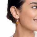 Woman wearing genuine Baltic honey amber drop earrings in 925 sterling silver, handcrafted in Poland, lightweight natural amber jewelry with warm golden tones, elegant everyday earrings shown on model outdoors