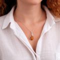 Model wearing genuine Baltic honey amber pendant necklace in 925 sterling silver, handcrafted teardrop amber jewelry on delicate silver chain, elegant women’s amber necklace close-up lifestyle photo