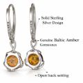 Pair of sterling silver amber drop earrings shown from the back on a light gray background, with callout labels highlighting “Solid Sterling Silver Design,” “Genuine Baltic Amber Gemstones,” and “Open back setting.” Visible 925 stamps appear on the leverback clasps and earring backs.